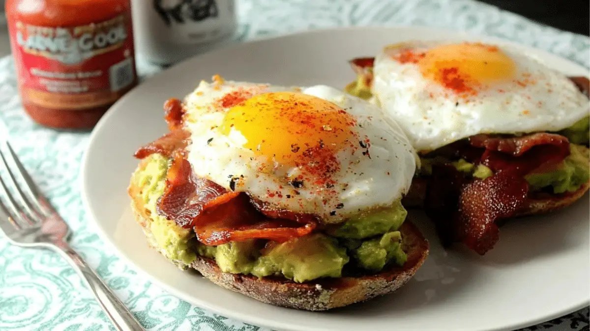 Avocado toast with crispy bacon and a perfectly cooked egg on a breakfast plate.
