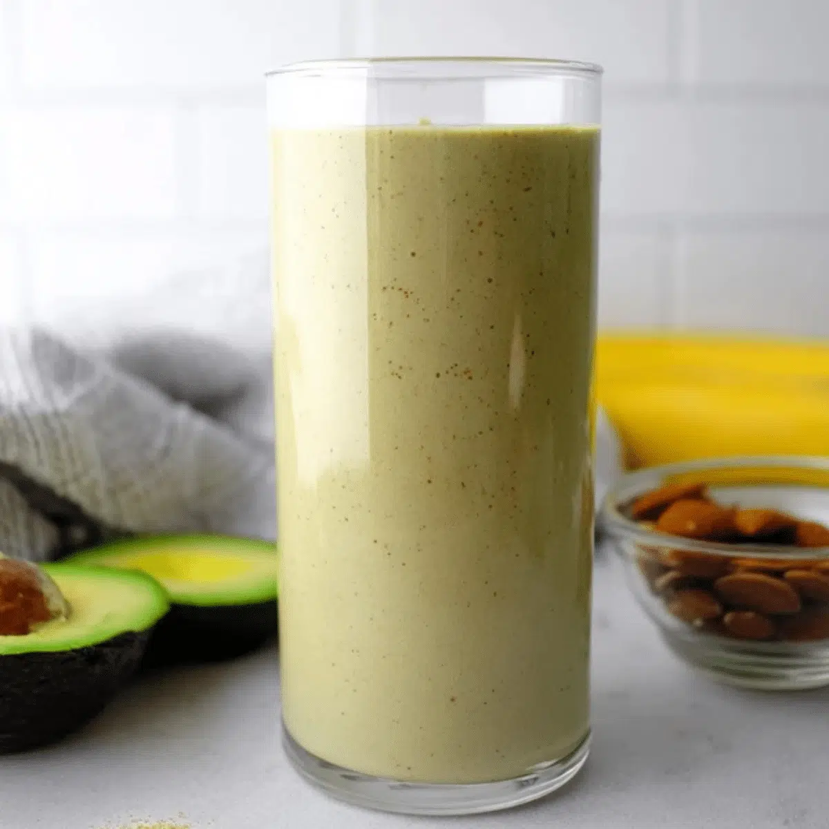 Creamy banana avocado almond milk smoothie in a glass with fresh ingredients.