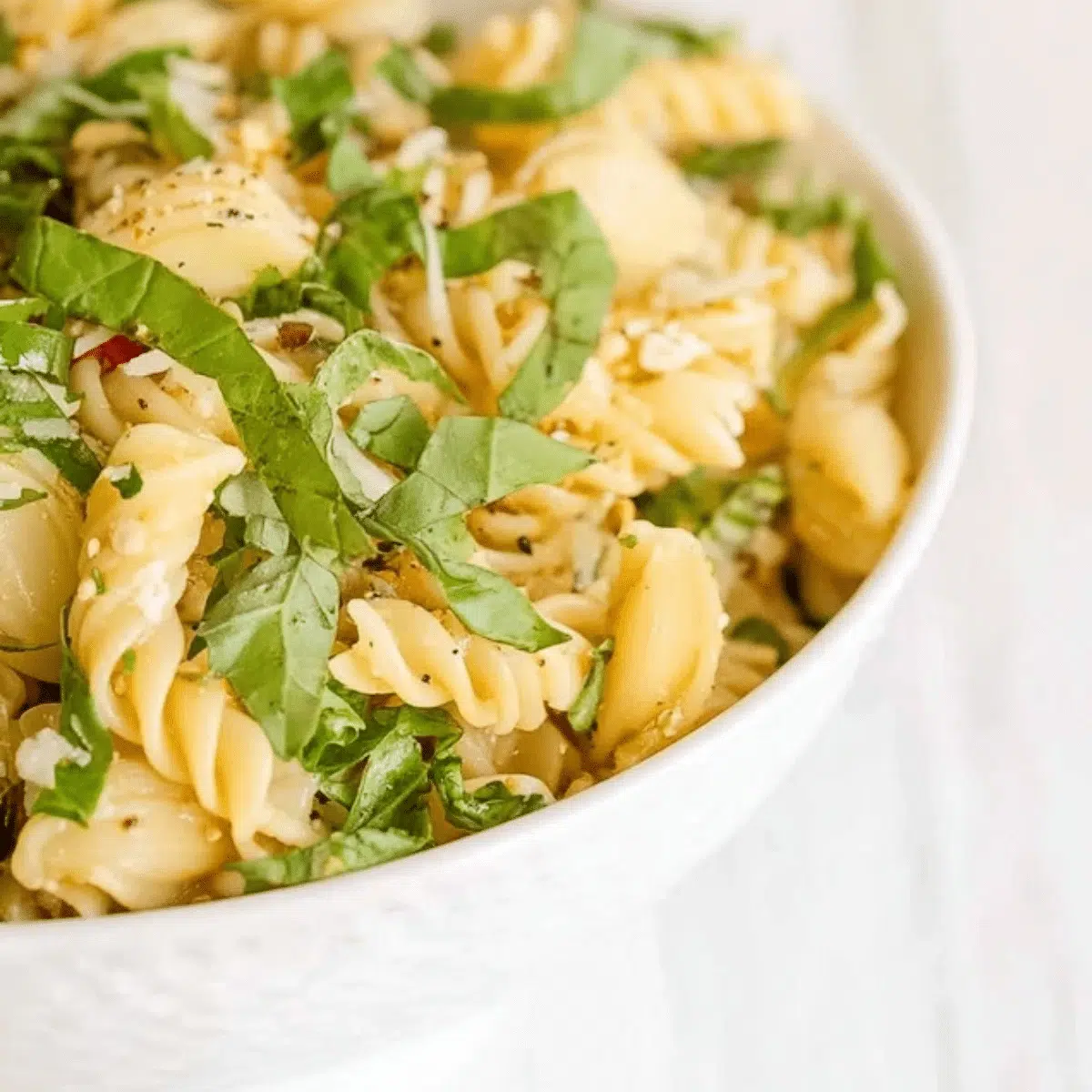 Lemon basil pasta salad in a bowl, garnished with fresh basil and lemon slices