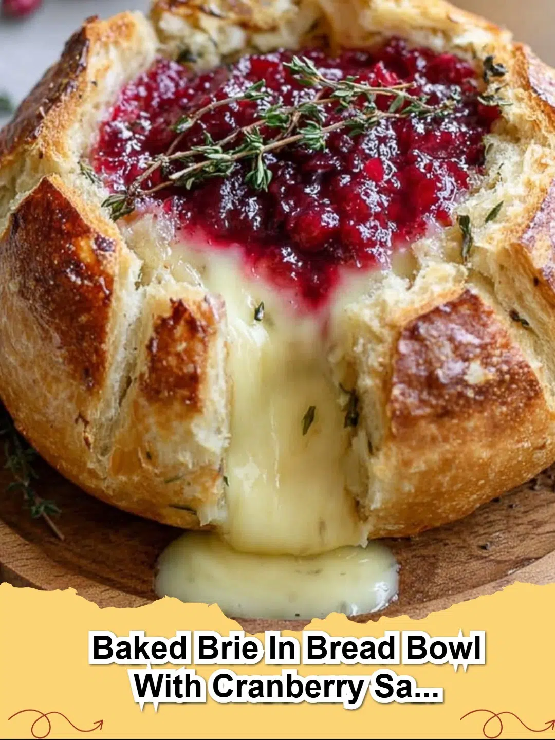 Baked Brie in a Rustic Bread Bowl with Cranberry Sauce and Fresh Thyme, ready to serve as an appetizer.