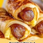 Golden brown Breakfast Pigs in a Blanket with scrambled eggs peeking out, on a plate with a side of ketchup.