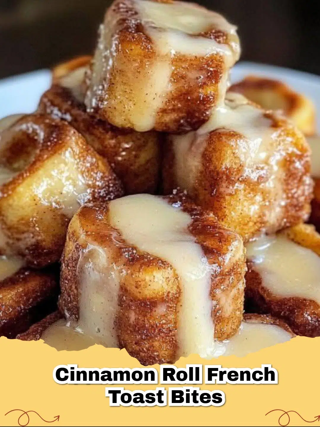 Pile of golden-brown Cinnamon Roll French Toast Bites drizzled with icing on a white plate