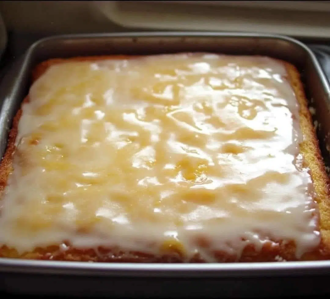 A perfectly baked Classic Lemon Cake with a bright yellow glaze drizzled over it, sitting on a cooling rack.