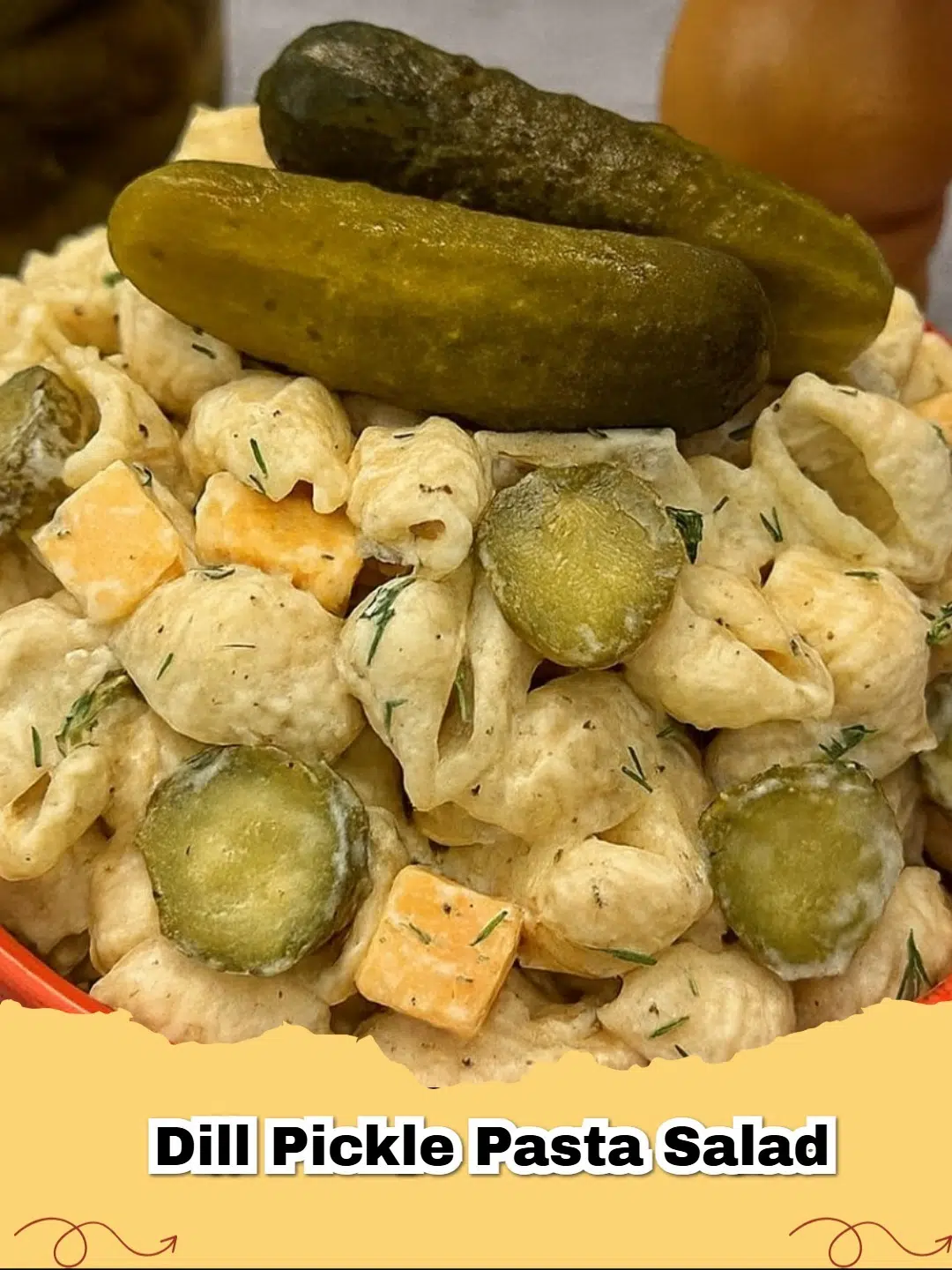 A vibrant bowl of Dill Pickle Pasta Salad with chopped fresh dill, cheddar cheese, and pickle slices, ready to serve.