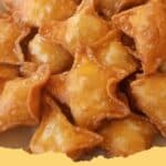 Crispy golden brown homemade Crab Rangoon appetizers arranged on a platter with dipping sauce
