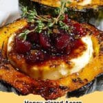 Two halves of Honey-Glazed Acorn Squash, filled with creamy goat cheese and drizzled with cranberries, on a white plate.