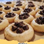 Close-up of freshly baked Italian Cannoli-Inspired Thumbprint Cookies on a cooling rack, showing creamy ricotta filling with chocolate chips and candied fruit.