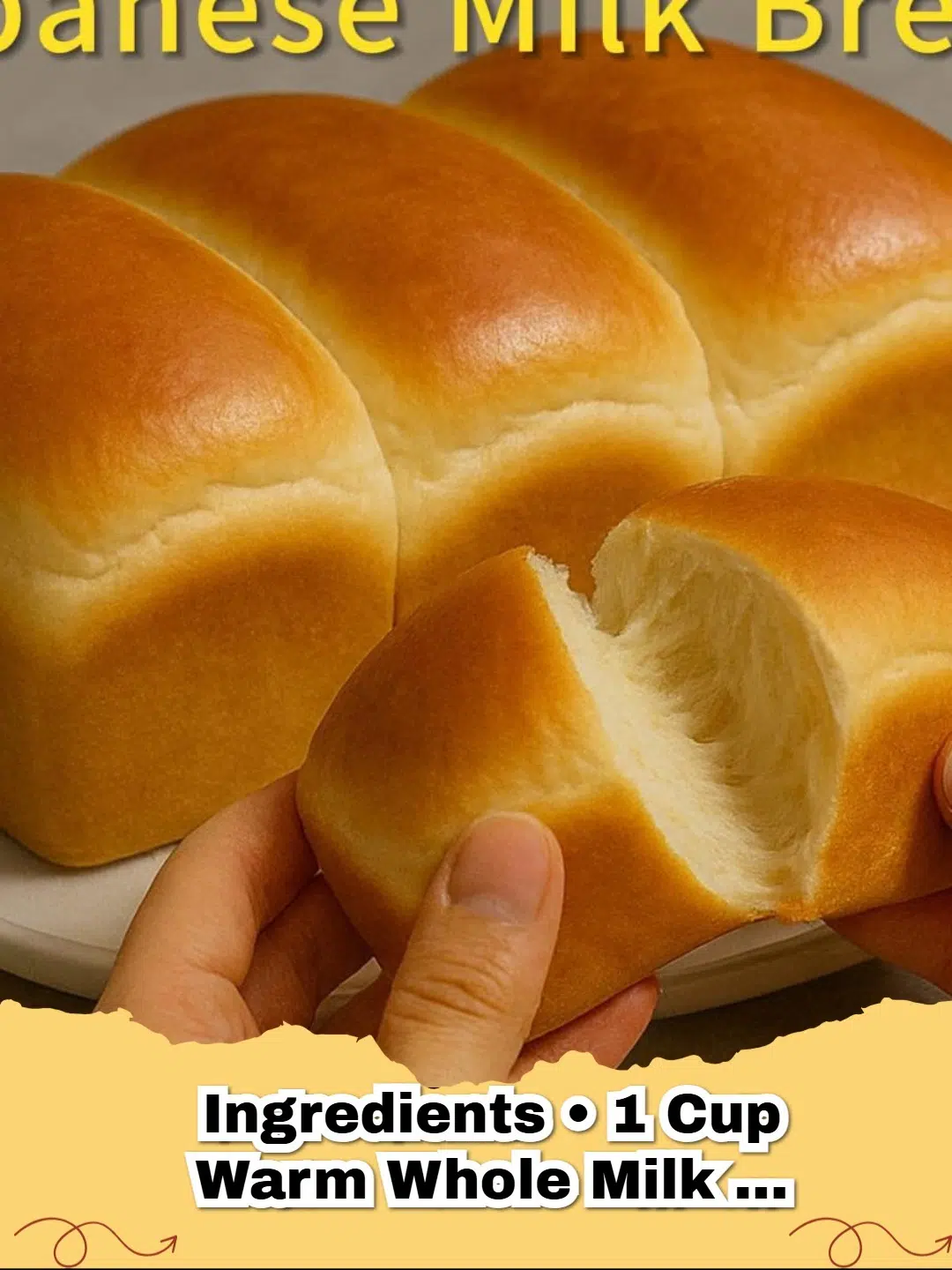 A golden brown loaf of Japanese Milk Bread with a soft, fluffy texture on a wooden board.