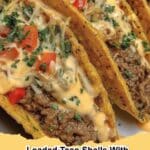 Loaded Taco Shells with Creamy Cheese Sauce, garnished with fresh cilantro and a dollop of sour cream on a wooden board