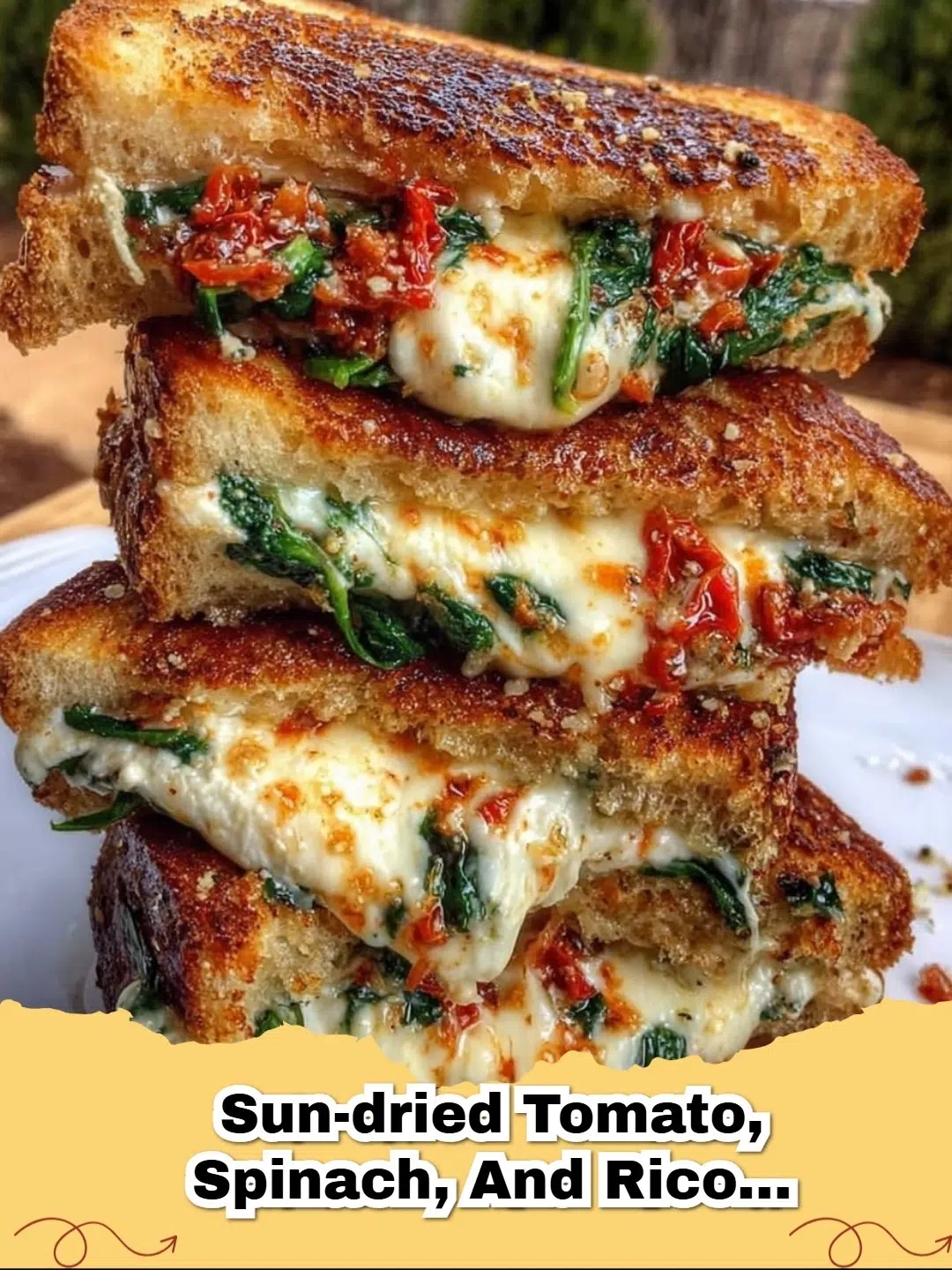 Delicious golden brown Sun-Dried Tomato, Spinach, and Ricotta Grilled Cheese sandwich cut in half on a plate