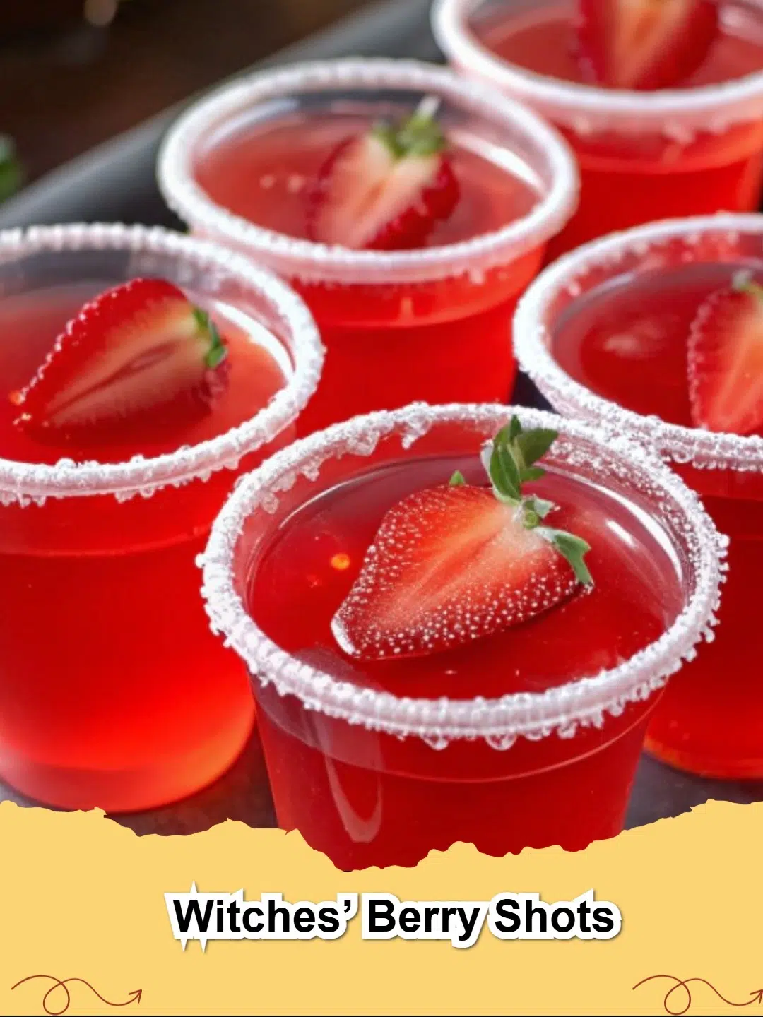 Vibrant red Witches' Berry Shots in shot cups, garnished with lime zest, perfect for a spooky Halloween party.