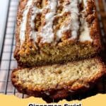 Slice of moist Cinnamon Swirl Banana Bread with a visible cinnamon ribbon, garnished with fresh bananas on a rustic wooden board.