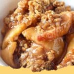 Close-up of a golden brown, bubbly classic apple crisp served warm in a baking dish.