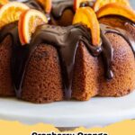 Vibrant Cranberry Orange Bundt Cake with a sweet orange glaze, garnished with fresh cranberries and orange zest, on a white plate.