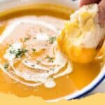 A bowl of creamy homemade pumpkin soup garnished with fresh sage and toasted pumpkin seeds.