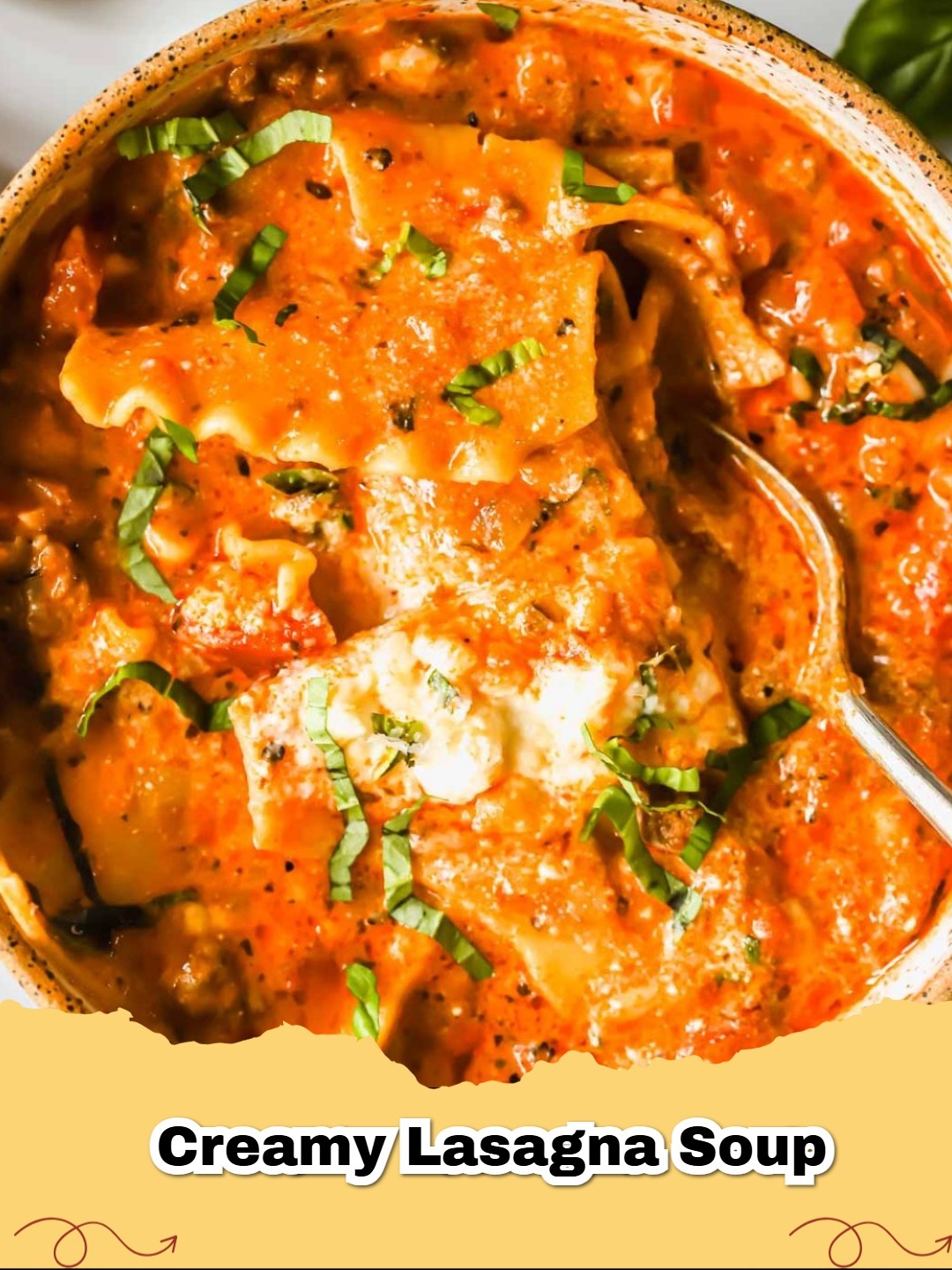 A close-up shot of a bowl of creamy lasagna soup garnished with fresh basil, mozzarella, and ricotta cheese, showing the noodles and ground beef.