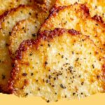 A close-up of golden brown crispy cottage cheese chips on a parchment-lined baking sheet, ready for a healthy snack.