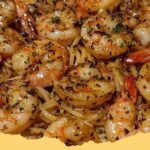 Close-up of a plate of delicious garlic butter shrimp pasta with spaghetti, red pepper flakes, and fresh parsley.