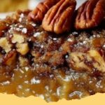 Close-up of a golden brown Pecan Pie Dump Cake fresh out of the oven, showing gooey pecan filling.