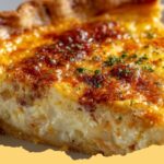 Close-up of a slice of golden-brown Green Chile Quiche with cheese and green chiles visible, ready to be served on a white plate.
