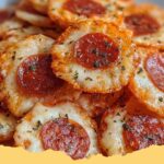 Crispy golden Keto Pizza Chips stacked on a white plate with a bowl of marinara sauce for dipping.