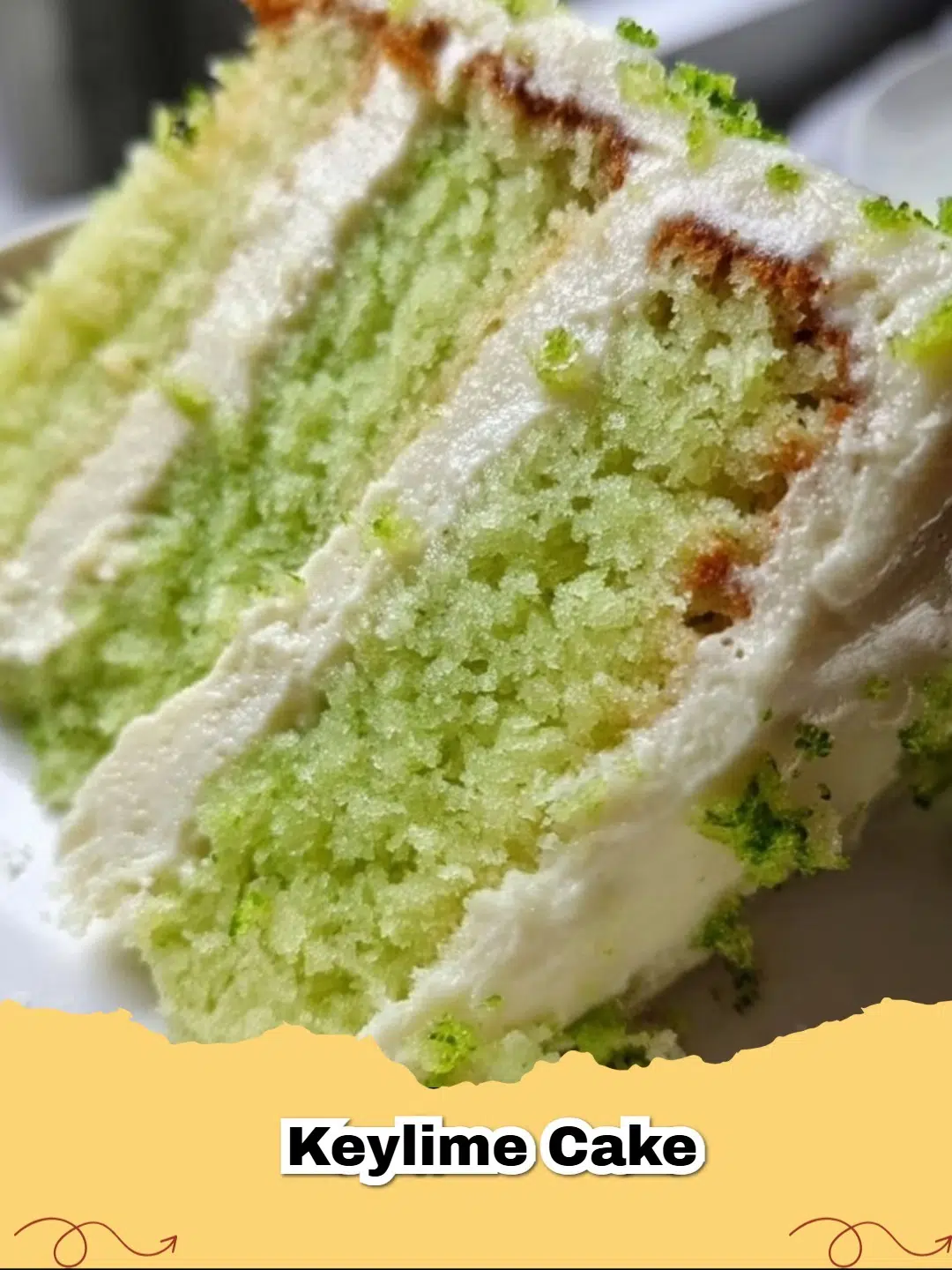 Delicious slice of vibrant green Key Lime Jello Cake with a fluffy white frosting and a lime wedge.
