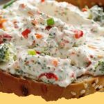 Creamy ranch veggie cream cheese spread with fresh vegetables on crackers.