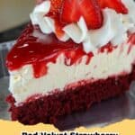 A stunning slice of Red Velvet Strawberry Cheesecake with layers of red cake and creamy white cheesecake, topped with glistening red strawberries.