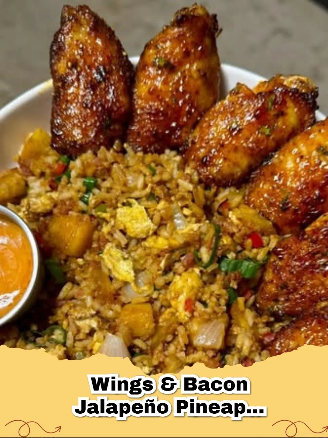 Platter of crispy chicken wings and bacon jalapeño pineapple fried rice drizzled with spicy yum yum sauce