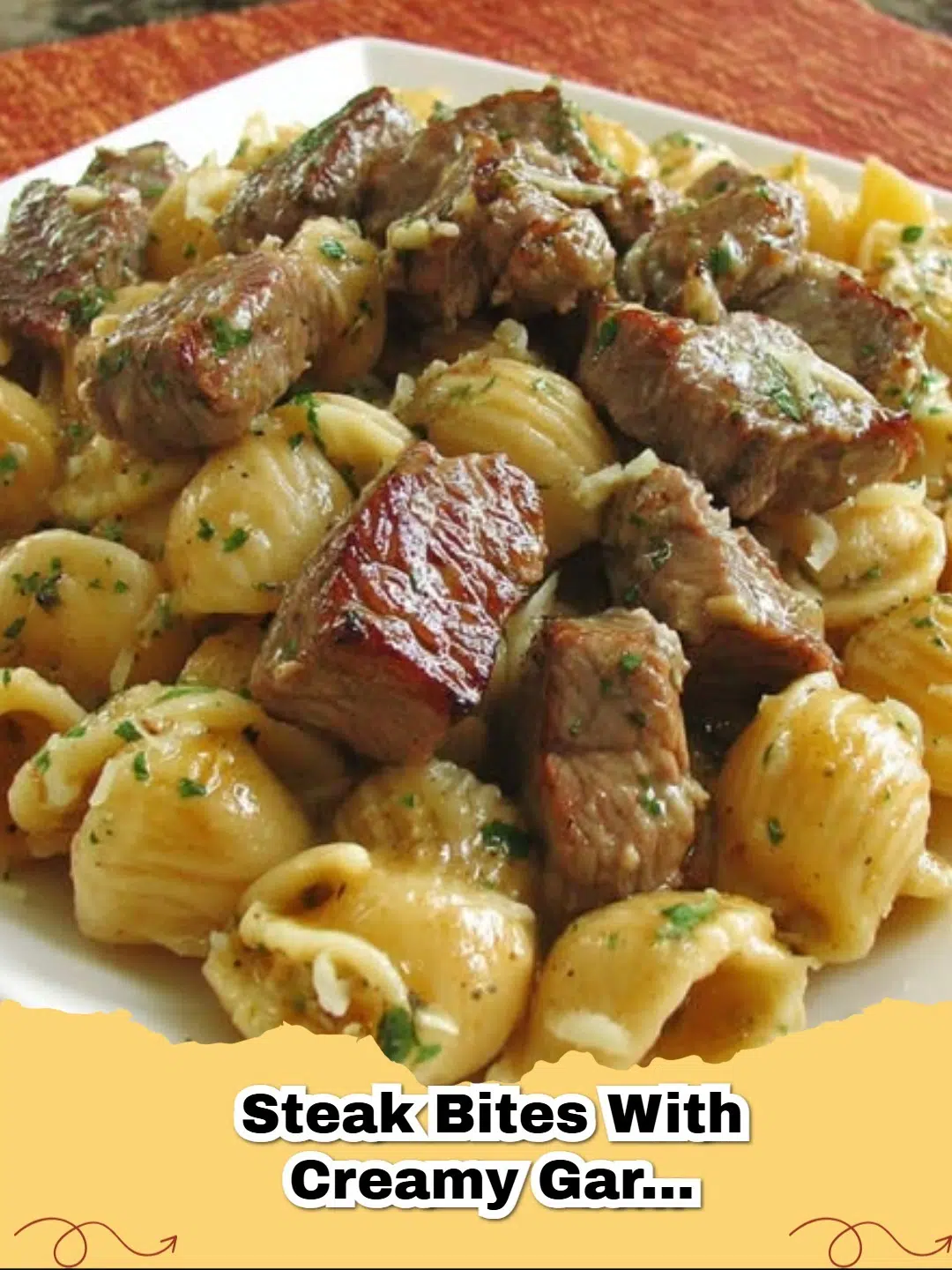 Close-up of juicy steak bites with creamy garlic parmesan shell pasta, garnished with fresh parsley.