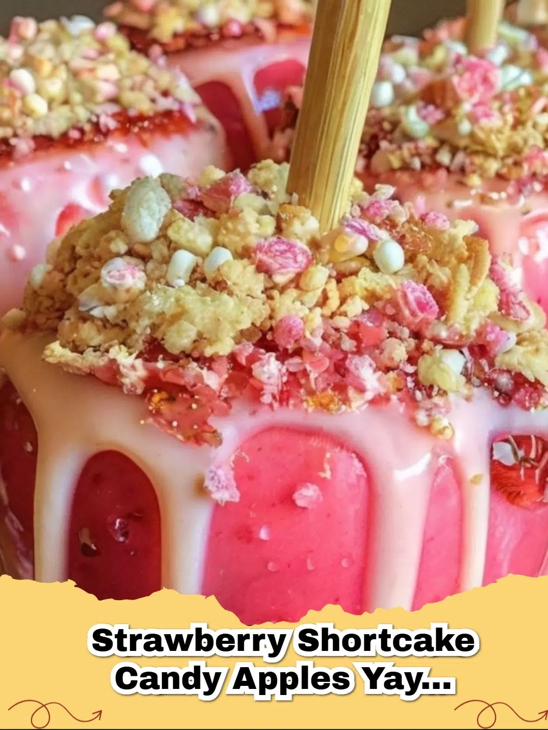 Four vibrant red apples coated in white chocolate and covered in golden shortbread crumbs, reminiscent of strawberry shortcake.