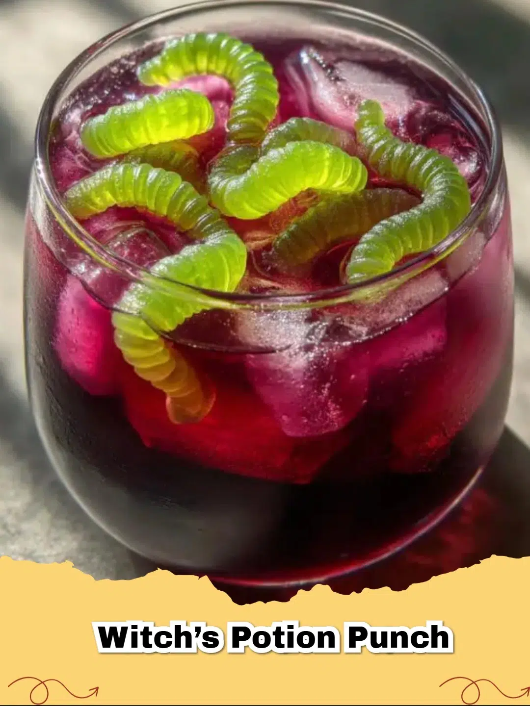 Vibrant purple Witch's Potion Punch in a large glass punch bowl with gummy worms and a spooky foggy effect from dry ice.
