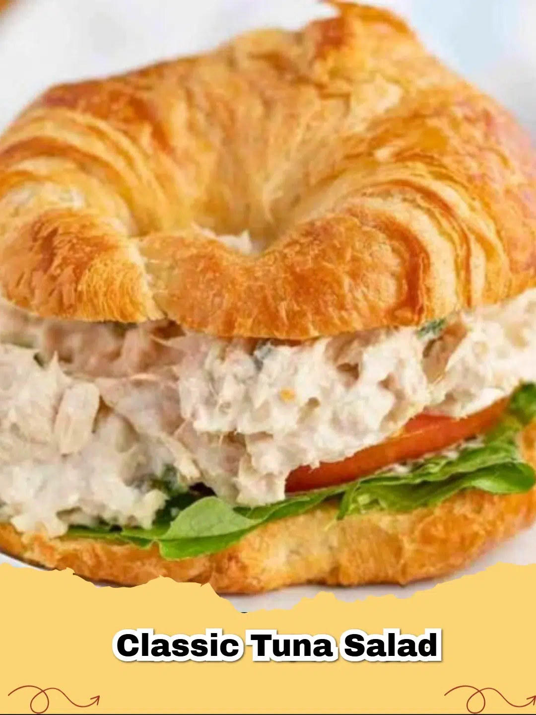 Close-up of creamy classic tuna salad in a white bowl with a spoon, garnished with fresh parsley.