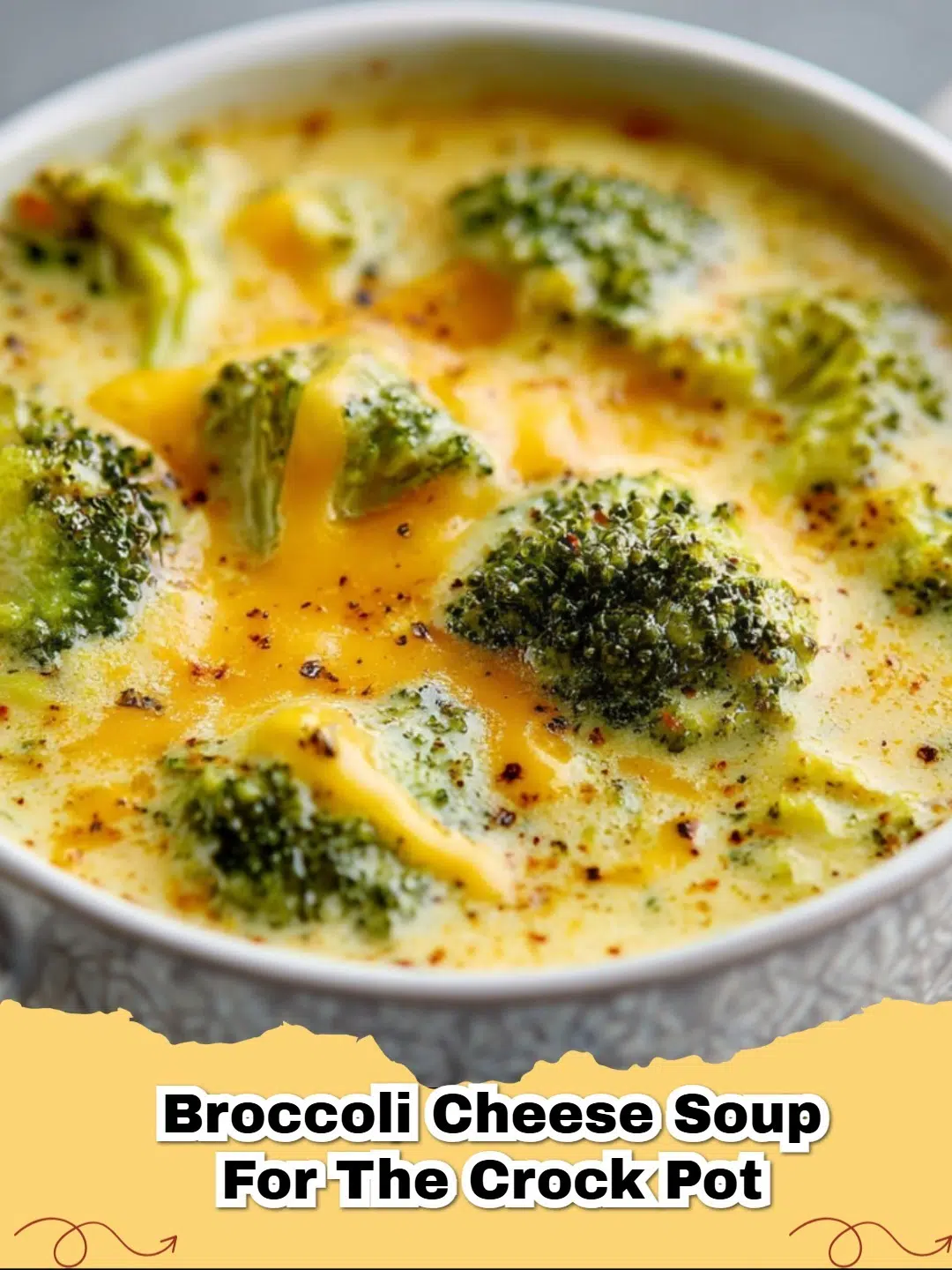 A steaming bowl of creamy Crock Pot Broccoli Cheese Soup topped with fresh broccoli florets and shredded cheddar cheese.
