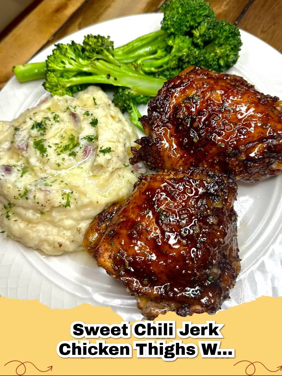Platter of crispy sweet chili jerk chicken thighs with creamy mashed potatoes and vibrant green broccolini, garnished with fresh herbs.