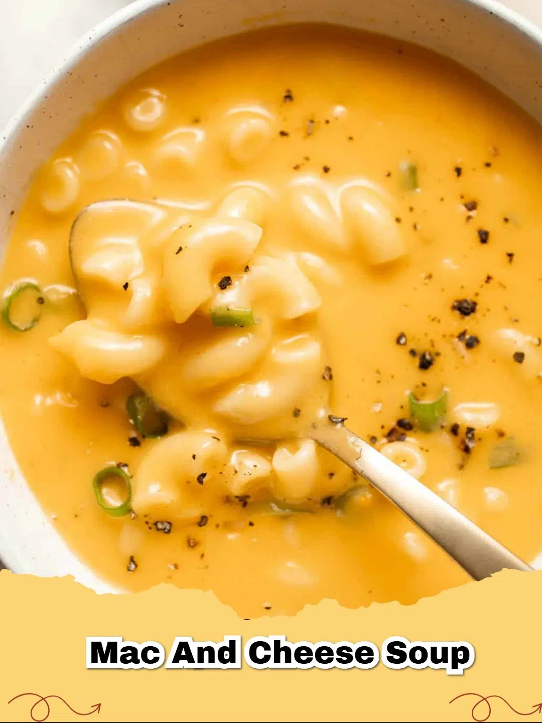 A steaming bowl of creamy mac and cheese soup garnished with fresh green onions and black pepper.