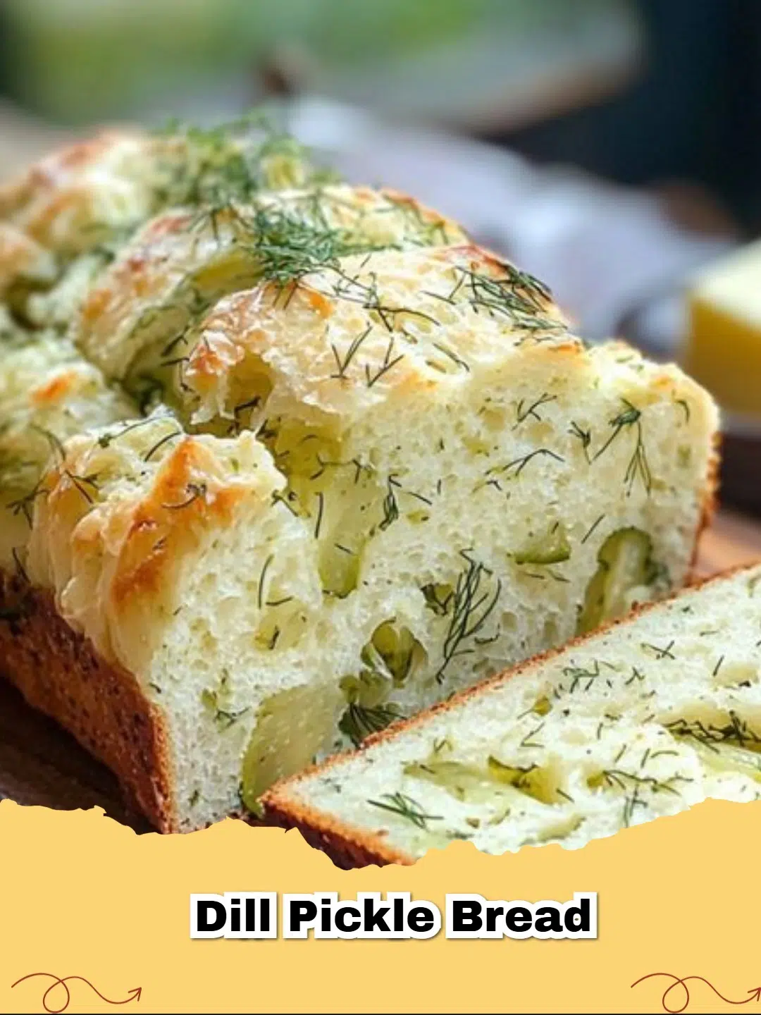 A freshly baked loaf of golden brown dill pickle bread on a wire rack, sliced to show the soft interior with flecks of dill and pickles.