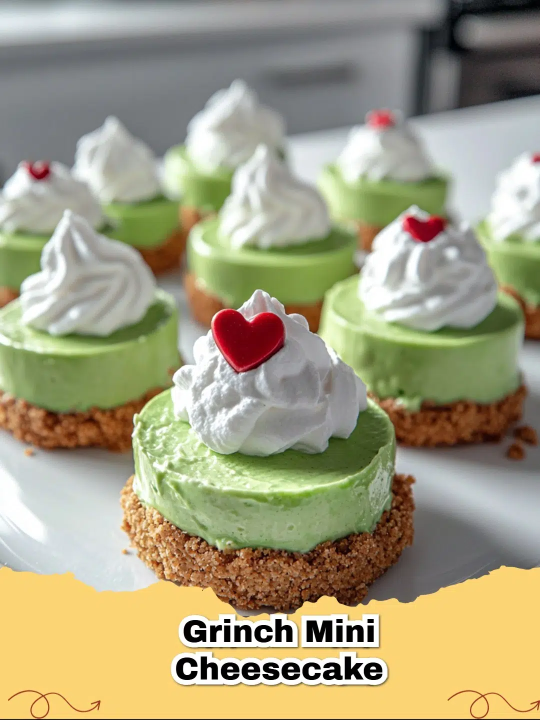 Festive Grinch Mini Cheesecakes with vibrant green filling, topped with whipped cream and a small red heart candy, ready for Christmas.