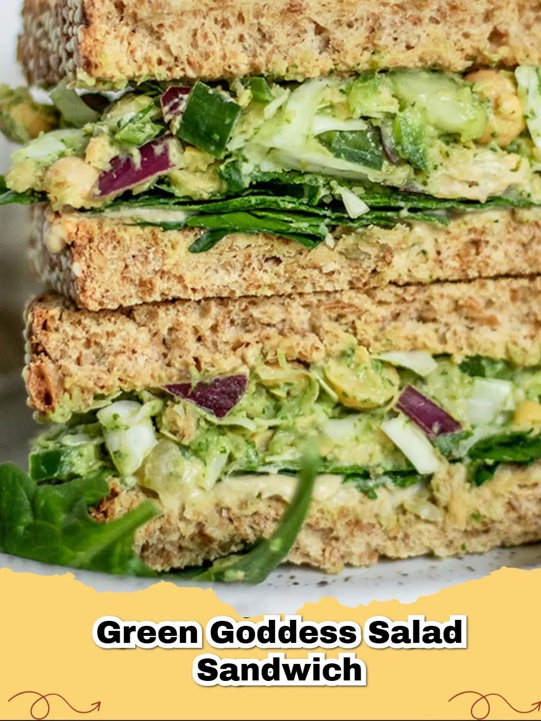 Two halves of a vibrant Green Goddess Salad Sandwich filled with crunchy vegetables and creamy dressing on toasted bread.