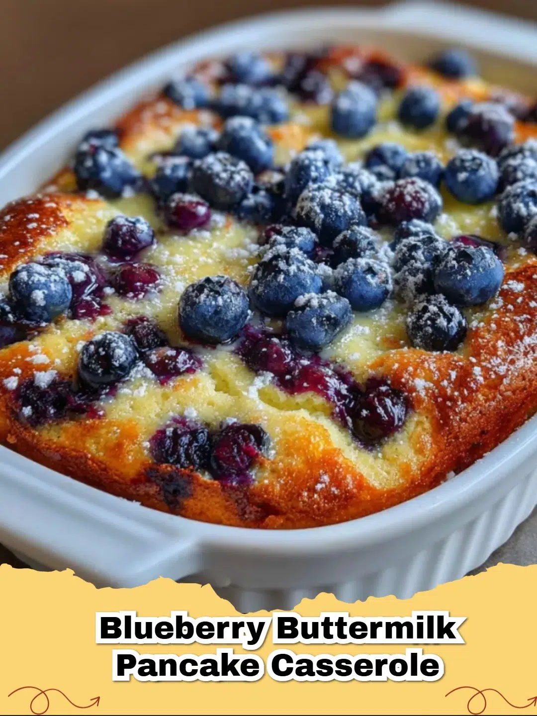 Close-up of baked Blueberry Buttermilk Pancake Casserole, dusted with powdered sugar and garnished with fresh blueberries.