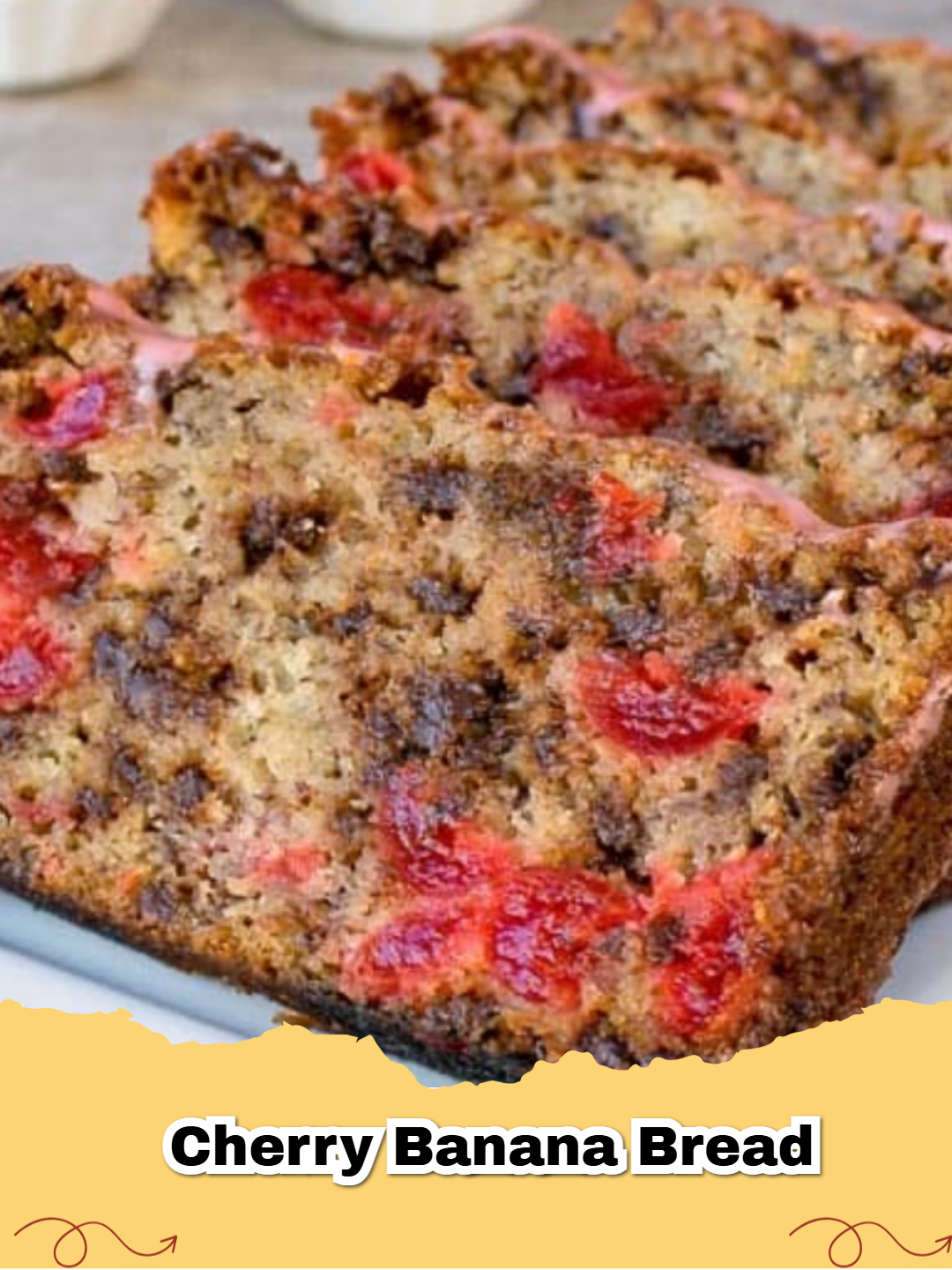 A close-up of a slice of Chocolate Chip Cherry Banana Bread showing red cherries and chocolate chips.