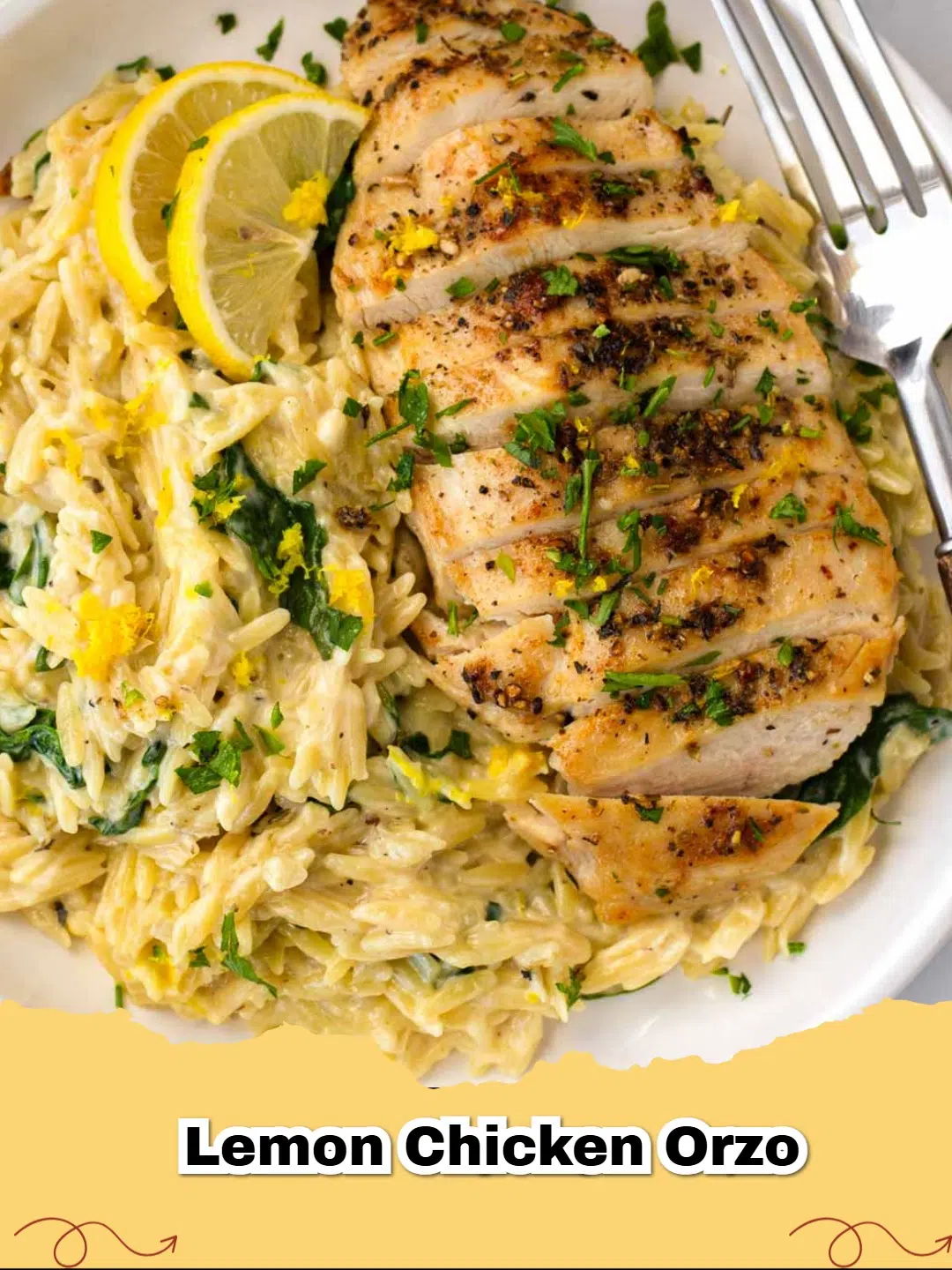 A close up of creamy Lemon Chicken Orzo garnished with fresh parsley and lemon slices in a black skillet.