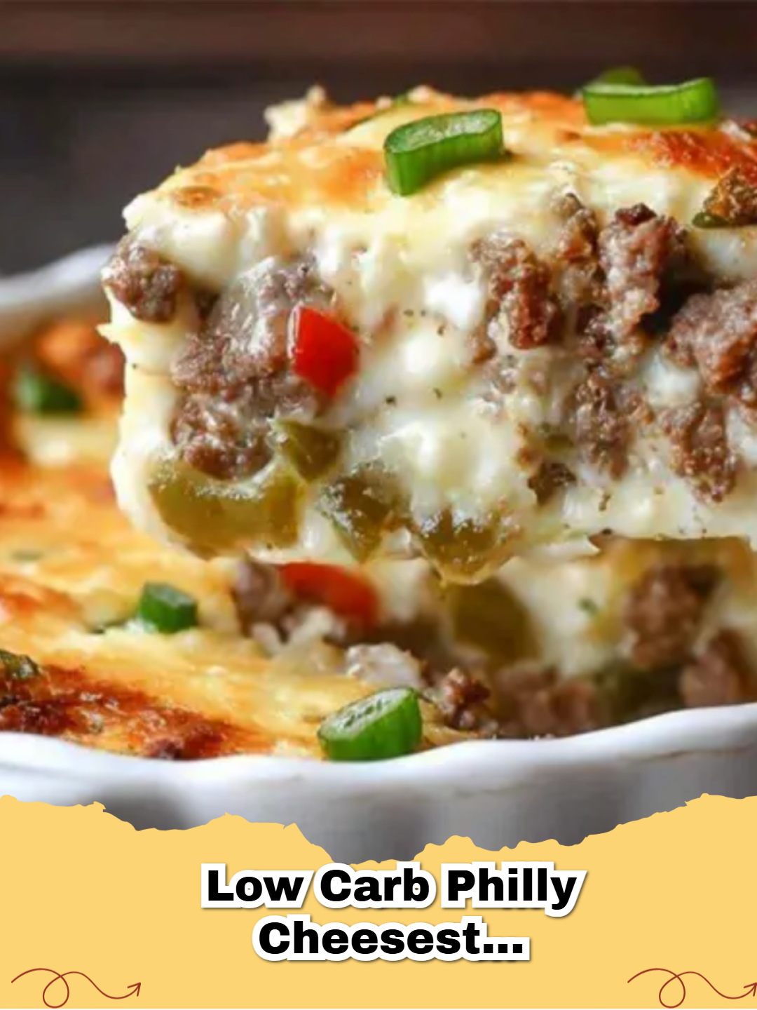 A close-up view of a cheesy Keto Philly Cheesesteak Casserole in a white baking dish.