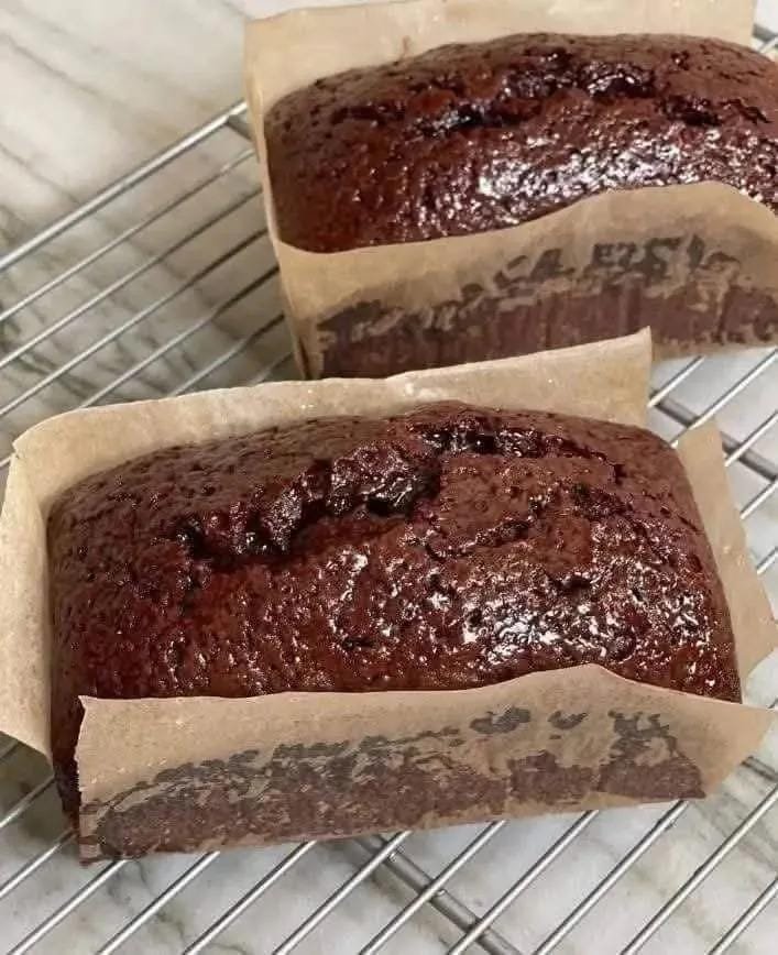 A thick slice of Moist Double Chocolate Loaf Cake showing its fudgy texture and chocolate chips.