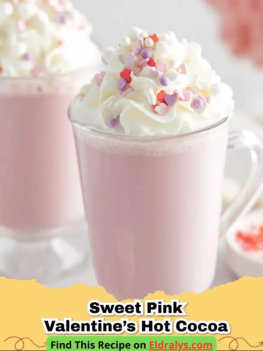 A mug of creamy Pink Valentine's Day Hot Chocolate topped with whipped cream and red heart sprinkles.