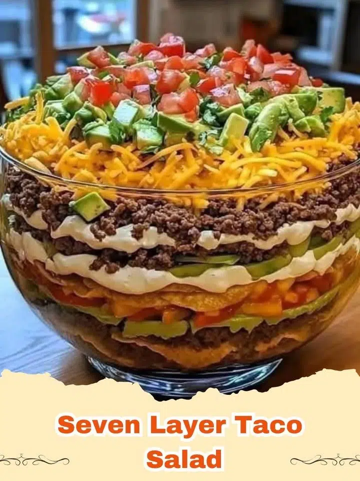 A close up shot of a colorful Seven Layer Taco Salad in a glass bowl showing all the distinct layers.