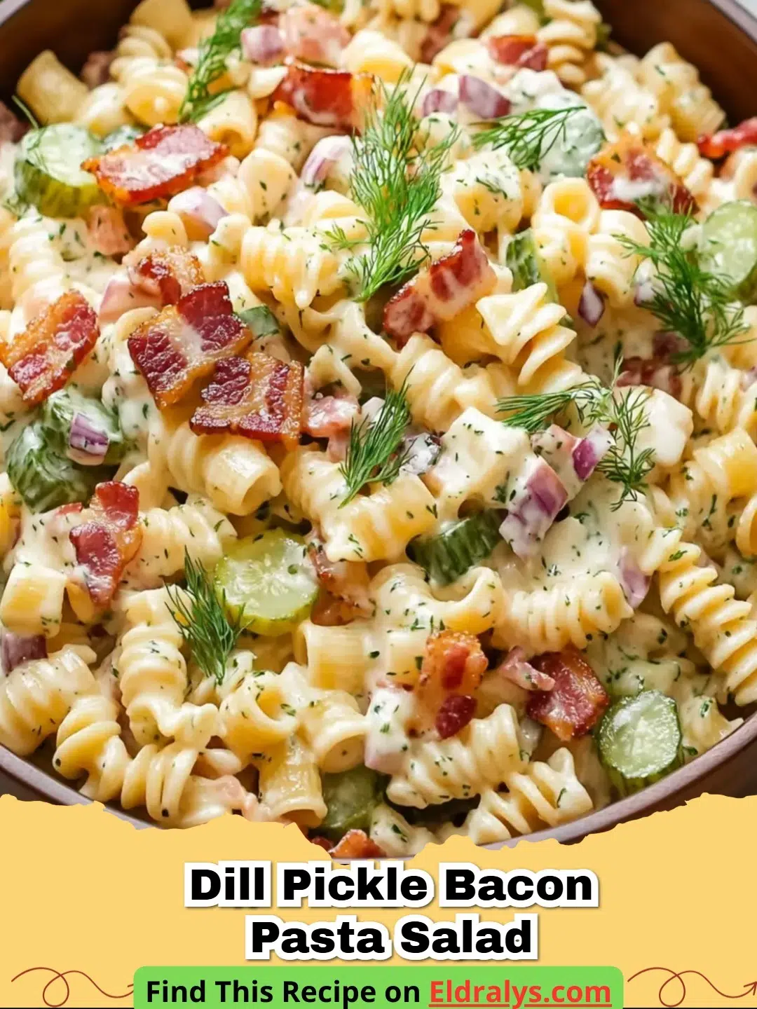 A close up shot of creamy Dill Pickle Bacon Pasta Salad in a glass bowl featuring fresh dill and crispy bacon.