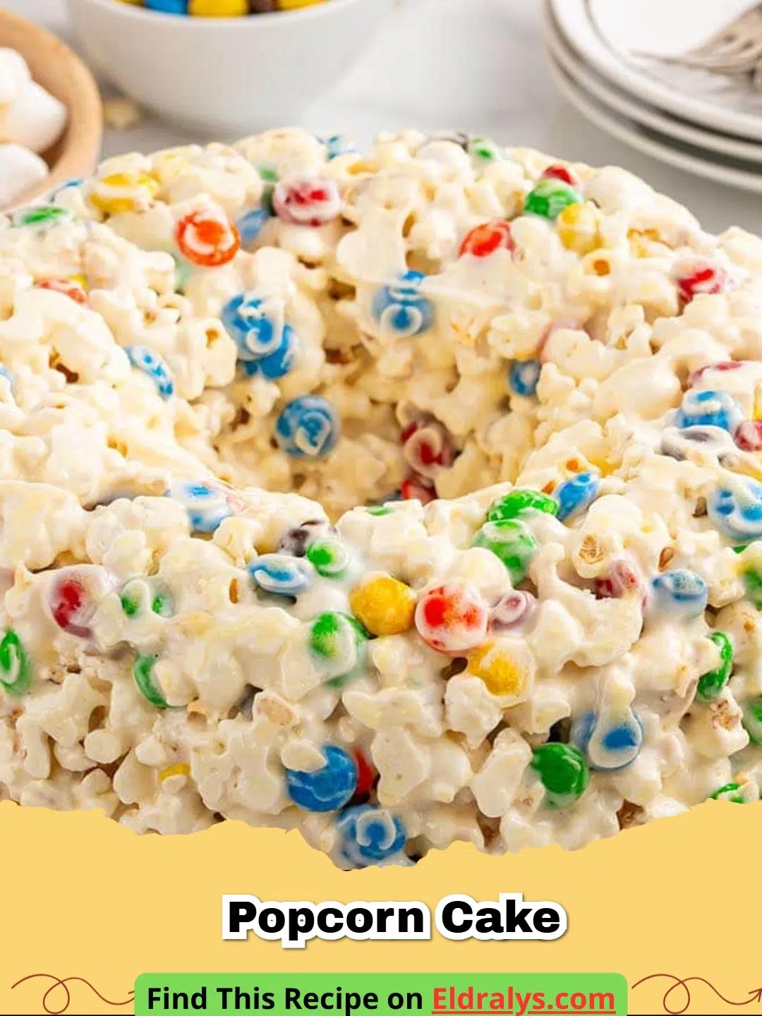 A colorful Easy Marshmallow Popcorn Cake with M&M's shaped in a Bundt pan.