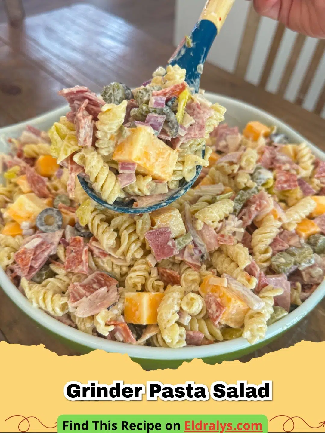 A close up view of a colorful Grinder Pasta Salad in a glass bowl featuring rotini, salami, and peppers.