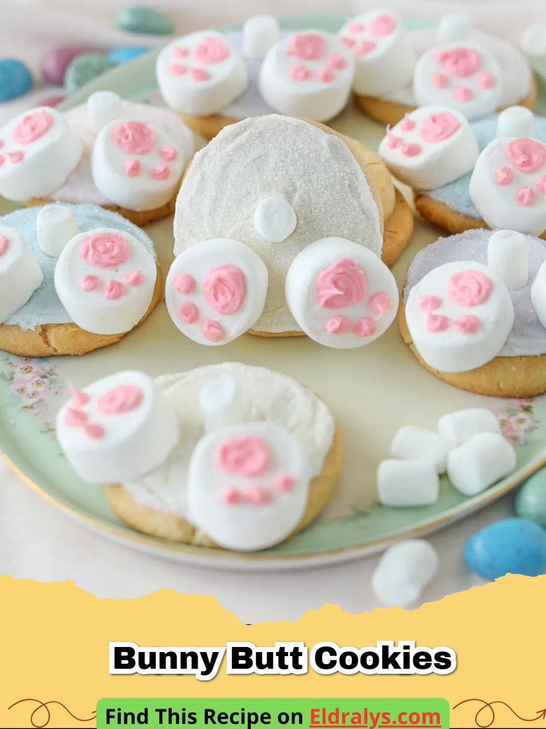 Close-up of several Bunny Butt Cookies with marshmallow feet and coconut tails on a green surface.